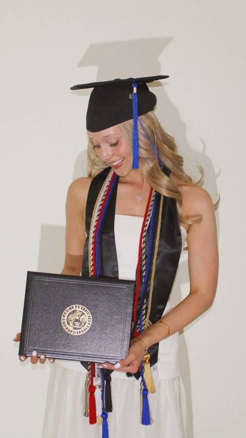 Olivia Anderson at her graduation, smiling at her diploma